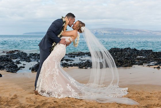 A morning Maui beach wedding under soft light with a floral arch